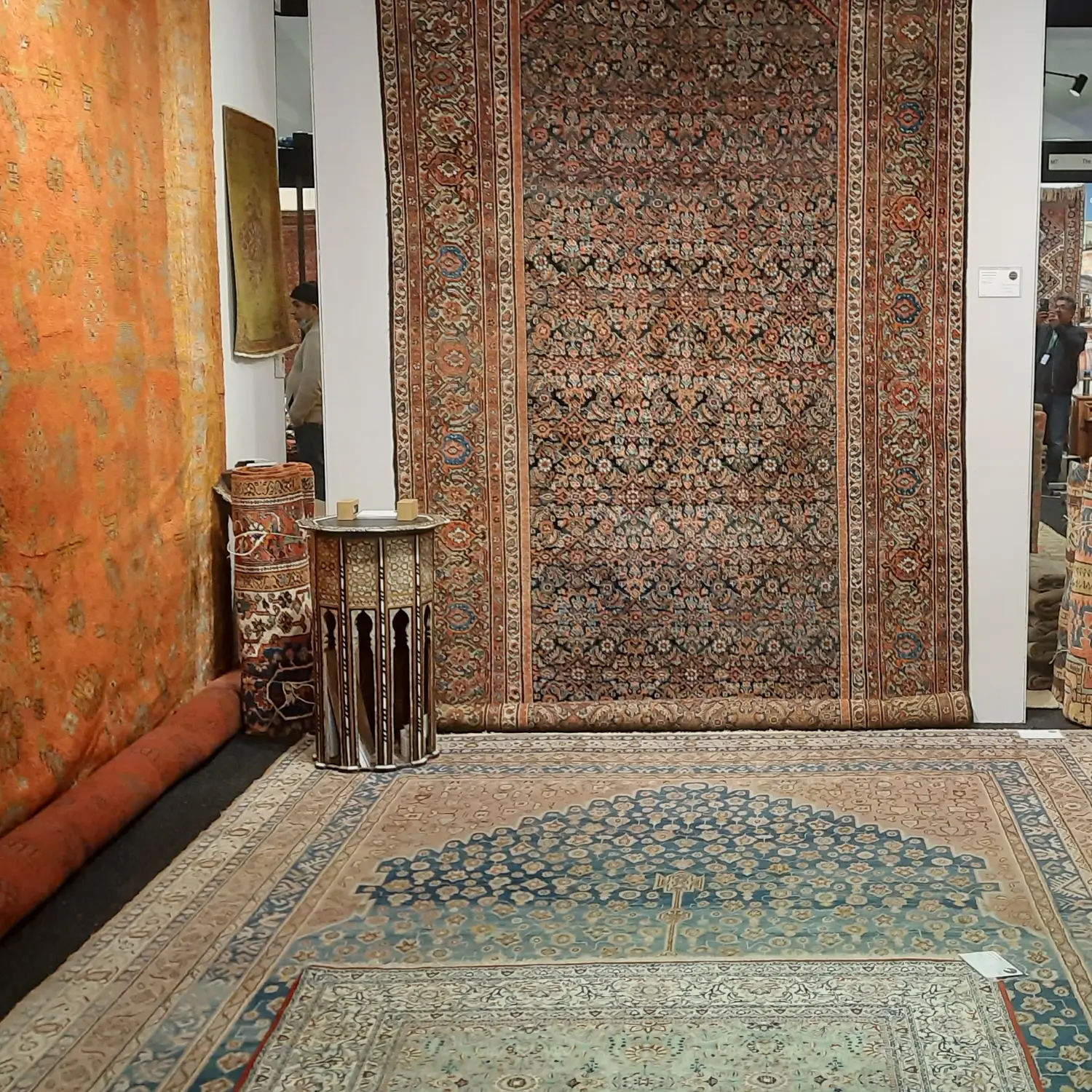 Visitors viewing embroidered suzani textiles on a dealer's stand at LARTA